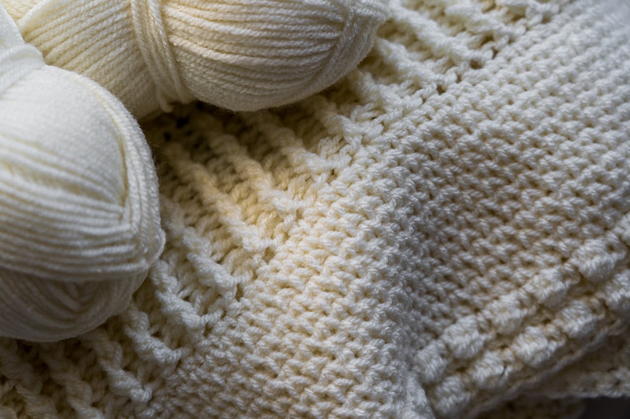 Macro shot of cream wool yarn and knitted fabric showcasing texture and detail.